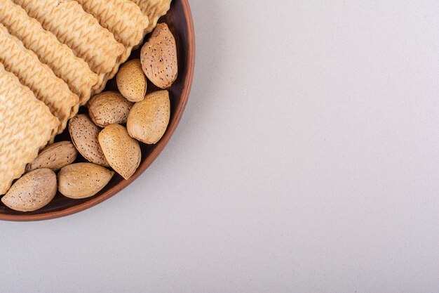 Plate of shelled organic almonds and biscuits on white background. High quality photo