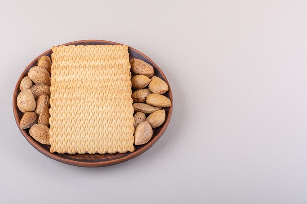 Plate of shelled organic almonds and biscuits on white background. High quality photo