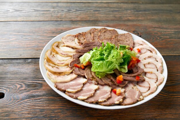 Plate of sliced assorted meat decorated with chopped salad on wooden table copyspace food eating tasty delicious meal dinner snack lunch restaurant cafe edibles vegetables.