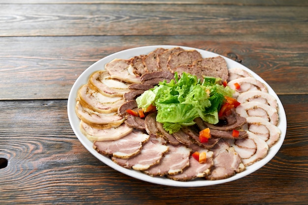 Plate of sliced assorted meat decorated with chopped salad on wooden table copyspace food eating tasty delicious meal dinner snack lunch restaurant cafe edibles vegetables.