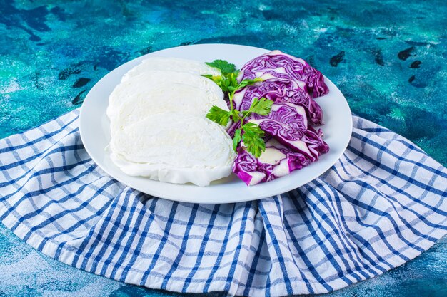 A plate of sliced cabbage and red cabbage on a towel