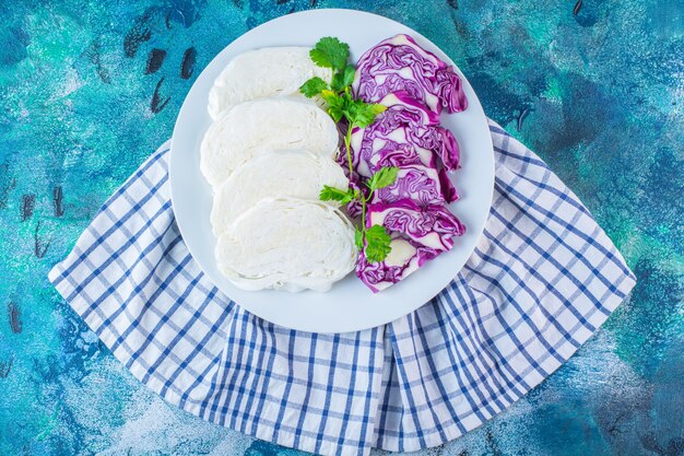 A plate of sliced cabbage and red cabbage on a towel