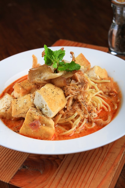 Plate of soup with spaghetti, bread pieces and decorated with greens