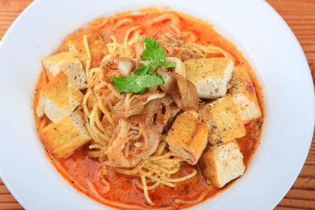 Тарелка супа со спагетти, кусочками хлеба и украшенная зеленью