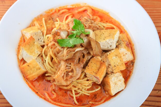 Plate of soup with spaghetti, bread pieces and decorated with greens