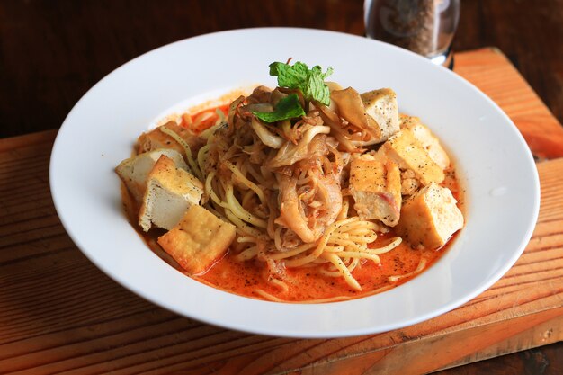 Plate of soup with spaghetti, bread pieces and decorated with greens