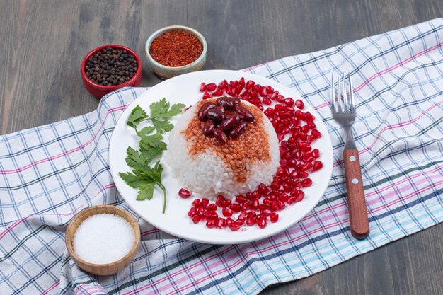 Plate of steamed rice with pomegranate seeds on tablecloth