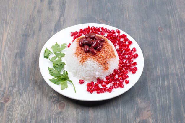 Free photo plate of steamed rice with pomegranate seeds on wooden surface