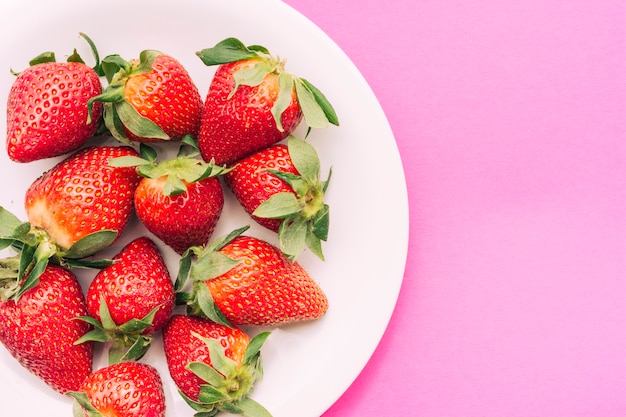 Plate of strawberries on pink background