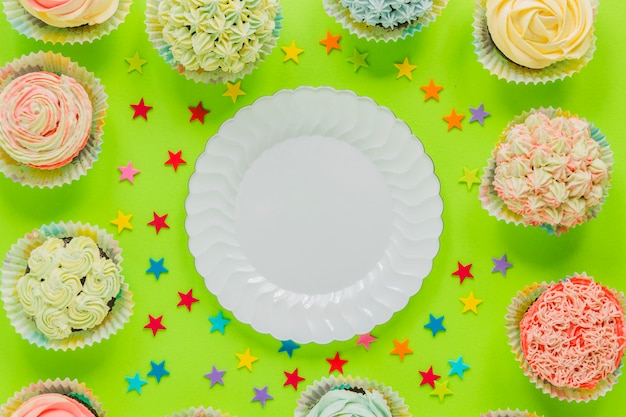 Free photo plate surrounded with cupcakes