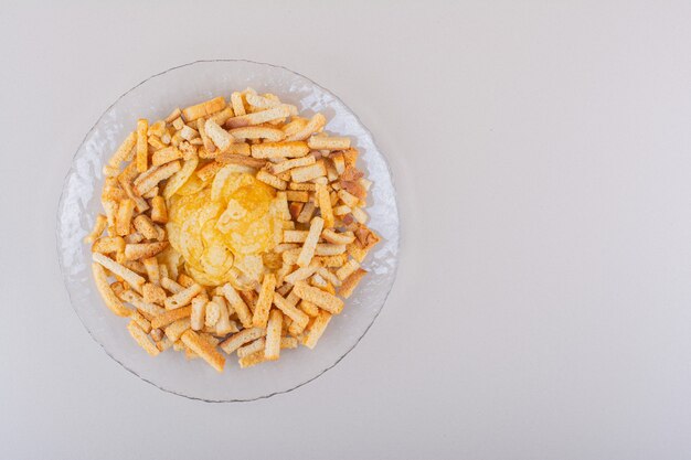 Plate of tasty crispy crackers and chips on white background. High quality photo