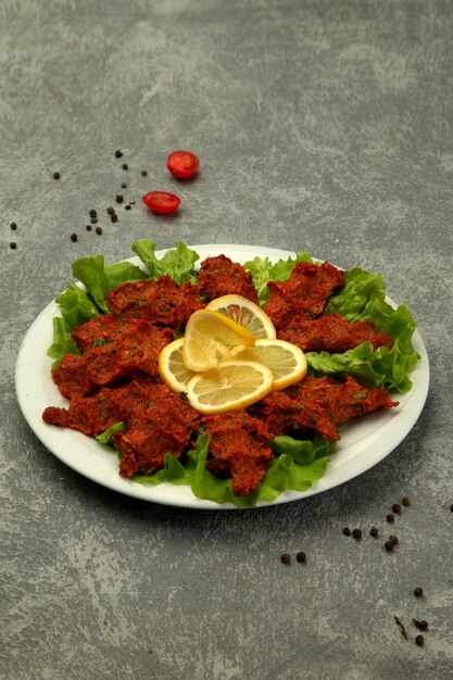 Plate of turkish chig kofte raw meatball with tomato paste and spice