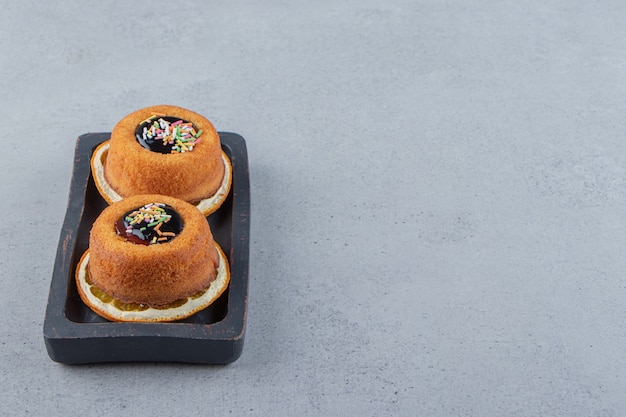 Plate of two mini cakes with jelly placed on top of slice of orange