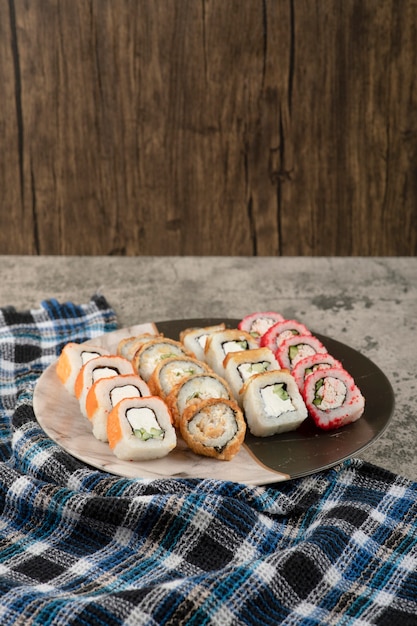 Piatto di vari deliziosi involtini di sushi sul tavolo di marmo