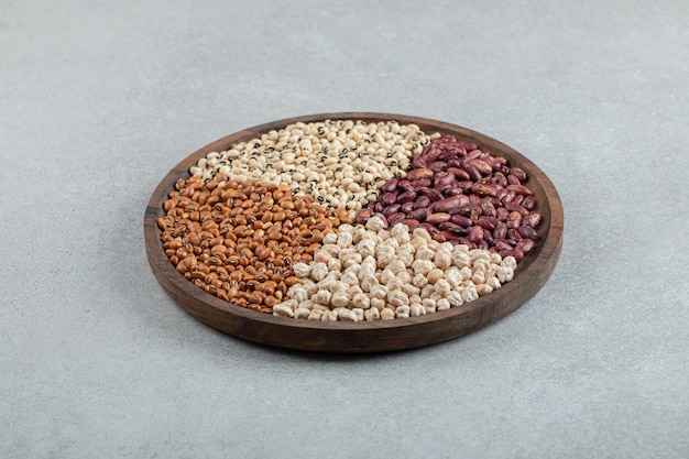 Plate of various dry pea and beans on marble surface.