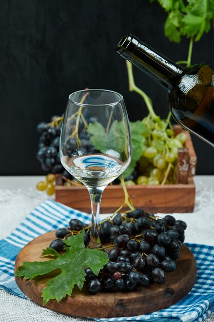 さまざまなブドウのプレートとワインボトル付きの白いテーブルにワインのグラス。高品質の写真