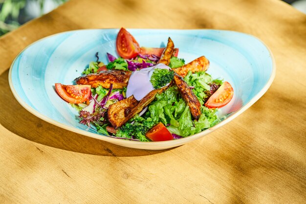 A plate of vegetable and chicken salad on wooden table