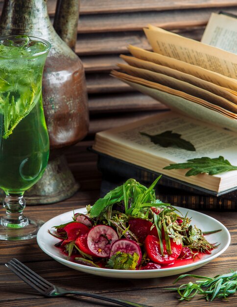 A plate of vegetable salad with a glass of green juice.