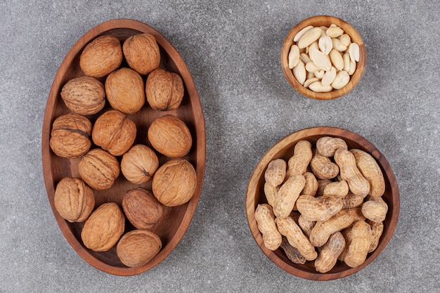 Free photo plate of walnuts, peanuts and cashew on marble surface