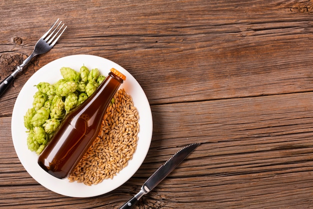 Plate with beer ingredients on wooden background