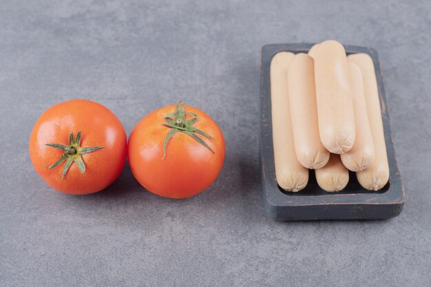 A plate with boiled sausages and red tomatoes 