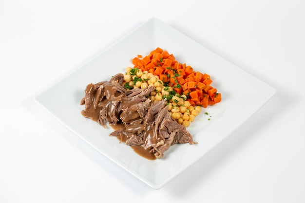 Plate with cooked beef peas and carrots with sauce