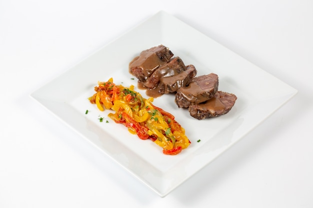 Plate with cooked beef with sliced colorful pepper covered with sauce