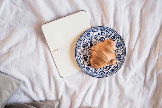 Plate with croissant and opened notebook