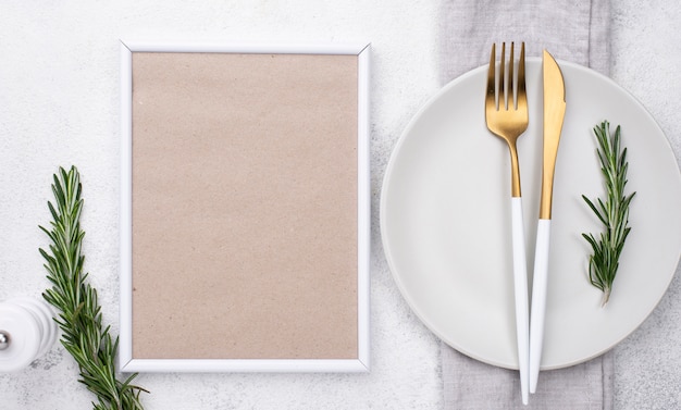 Free photo plate with cutlery and frame on table