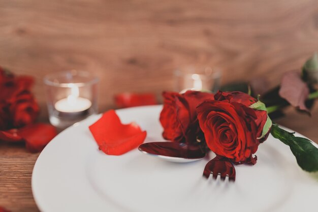 Тарелка с столовые приборы и розы крупным планом