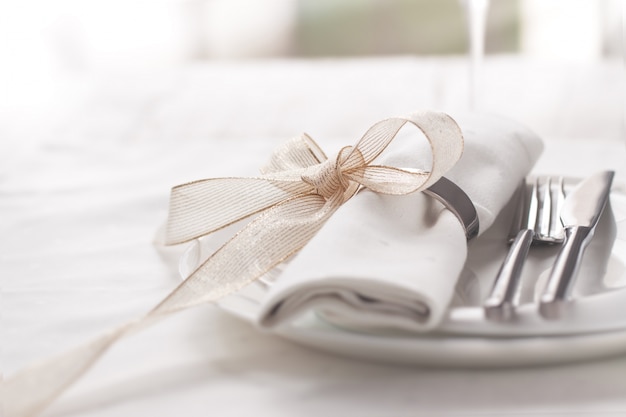 Plate with cutlery well decorated with napkin tied with a golden bow