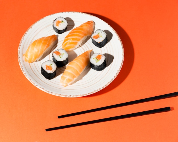 Plate with delicious variety of sushi and chopsticks