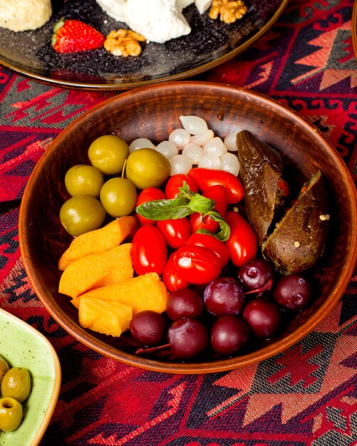 Тарелка с разными солеными огурцами, баклажанами, томатами черри и луком