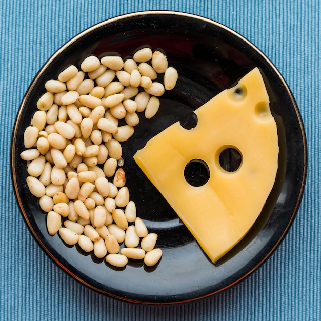 Free photo plate with fresh cheese and heap of nuts on table