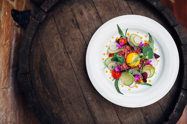 Plate with fresh salad on wooden barrel