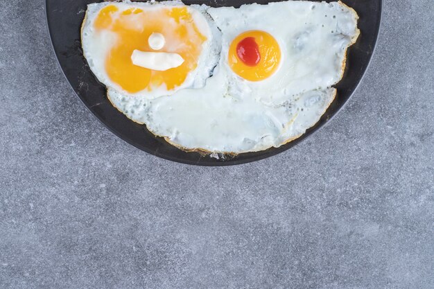 회색 표면에 계란 프라이가 있는 접시