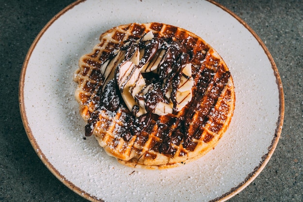 Free photo plate with gourmet waffles with chocolate and banana slices