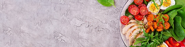 Foto gratuita piastra con un alimento dieta cheto. pomodorini, petto di pollo, uova, carota, insalata con rucola e spinaci. pranzo di keto. banner panoramico con copyspace. vista dall'alto