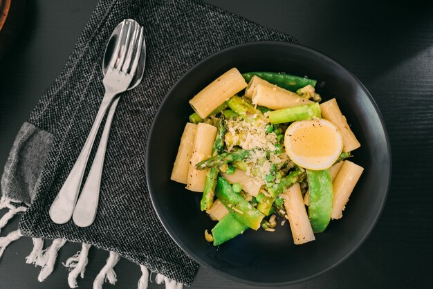 Plate with pasta asparagus and egg on a black table