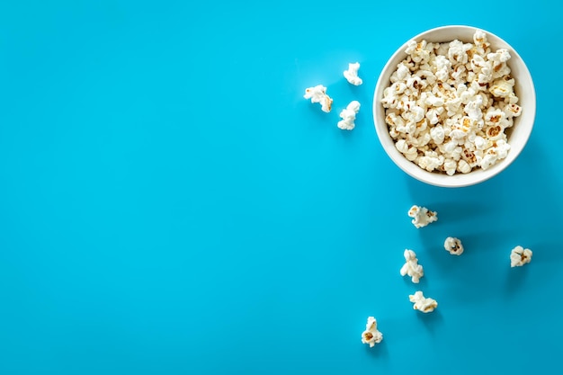 Free photo plate with popcorn on a blue background flat lay