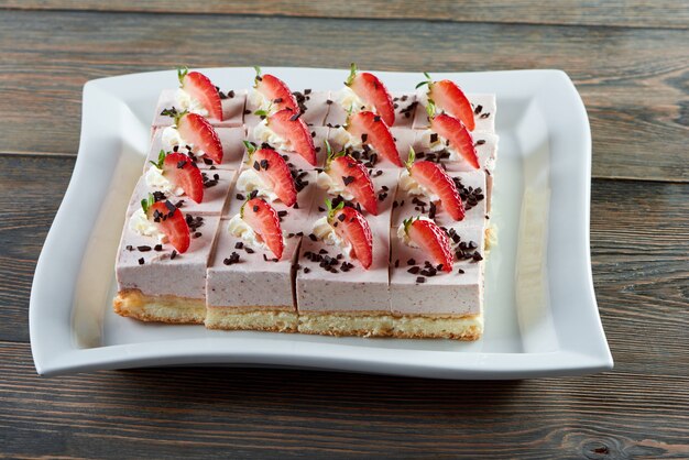 초콜릿 빵 껍질과 딸기로 장식 된 슬라이스 치즈 케이크 접시는 나무 테이블 레스토랑 카페 커피 숍 베이커리 베이킹 요리 과자 sweer 디저트 개념에 배치.