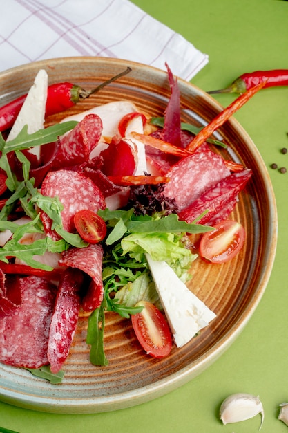 Plate with sliced salami, cheese and vegetables