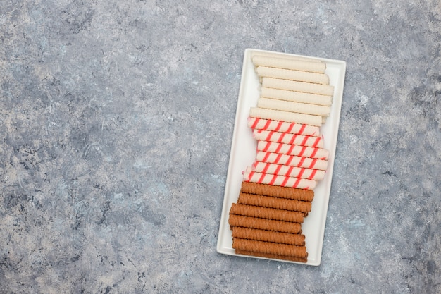 Free photo plate with tasty wafer roll sticks on concrete surface