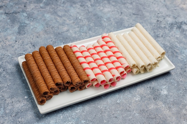 Plate with tasty wafer roll sticks on concrete surface