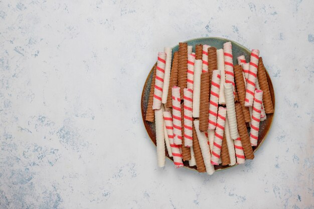 Plate with tasty wafer roll sticks on concrete surface