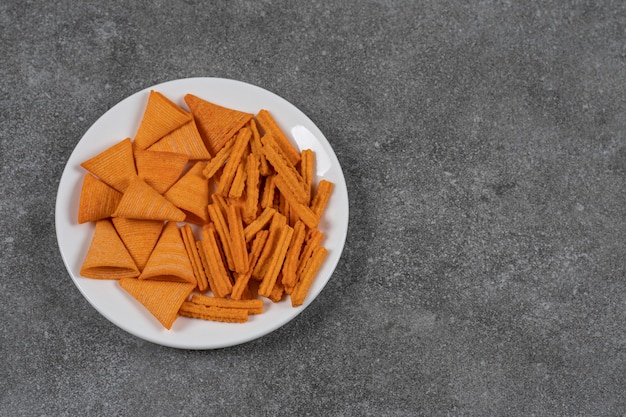 A plateful dried bread and corn chips  on the marble surface