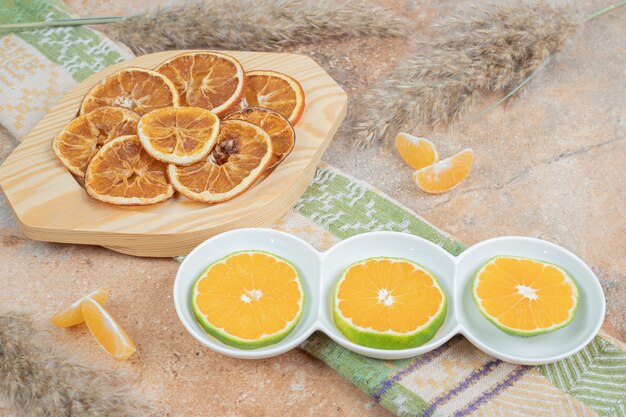 Plates of lemon slices and dried orange on marble surface.