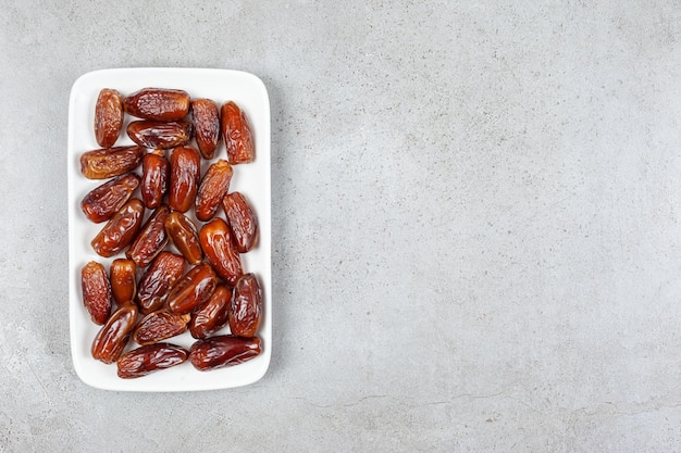Free photo a platter of appetizing dates on marble background. high quality photo