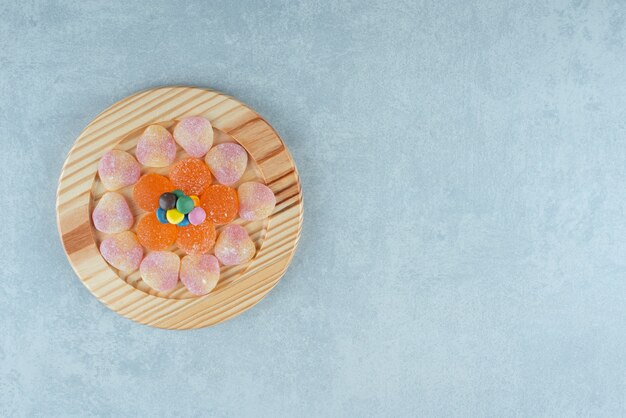 Platter of assorted marmelades with a few pieces of candy on marble.