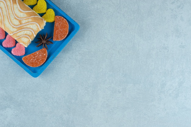 Free photo platter of cake roll with anises and marmelade bits on marble.